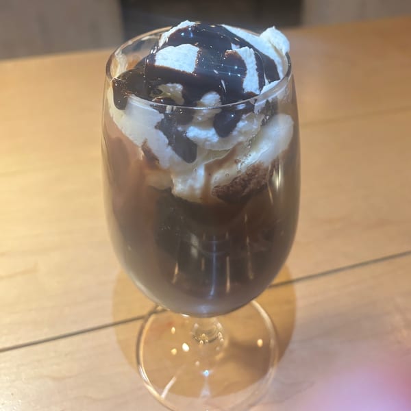 Chocolate dessert in a stemmed glass, topped with whipped cream and chocolate syrup.