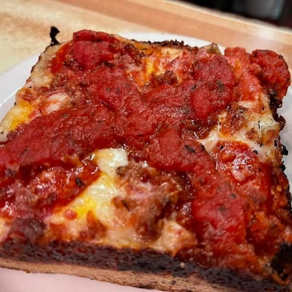 A thick slice of Junct'n Square Pizza with melted cheese, chunky tomato sauce, and pepperoni.